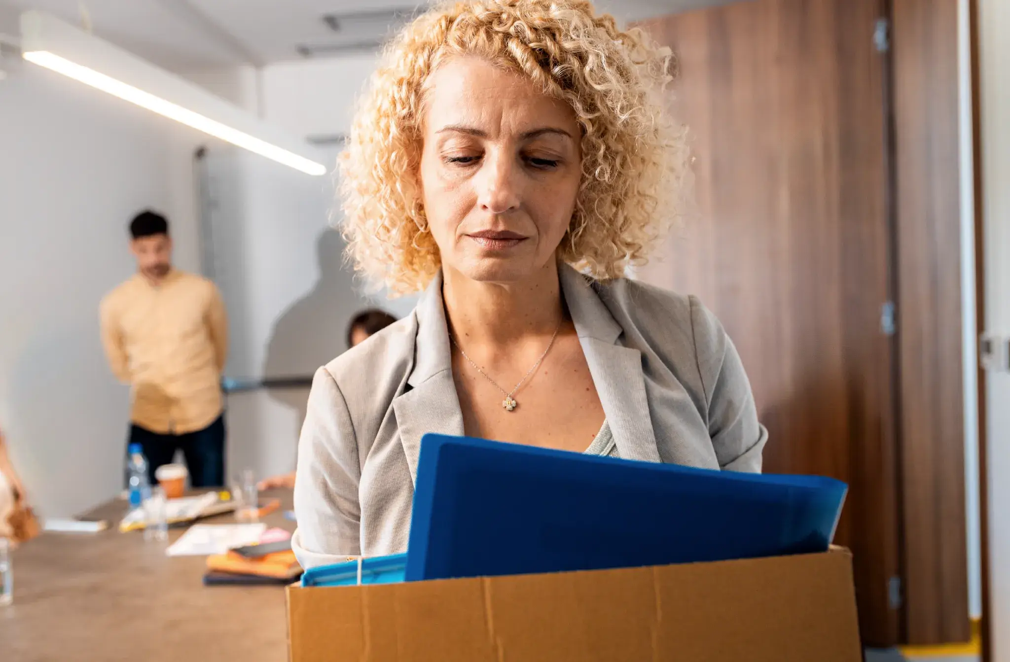 Employee carrying a box of belongings while leaving an office, illustrating wrongful termination and workplace dismissal claims.